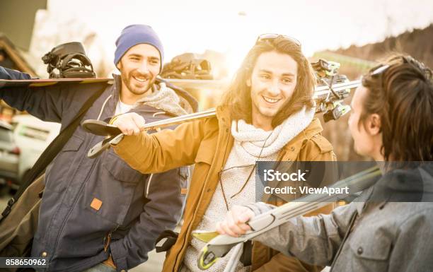 Best Friends Having Fun Together Walking With Ski And Snowboard At Mountain Trip Friendship Concept With Young People Hangout Loving Winter Sports Travel Warm Filter With Backlight Sunshine Halo Stock Photo - Download Image Now