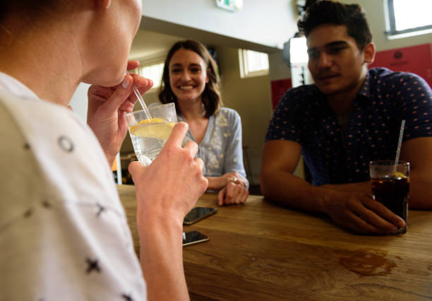молодые взрослые �в баре, веселясь, сосредотачиваются на выпивке - australia aborigine group of people friendship стоковые фото и изображения