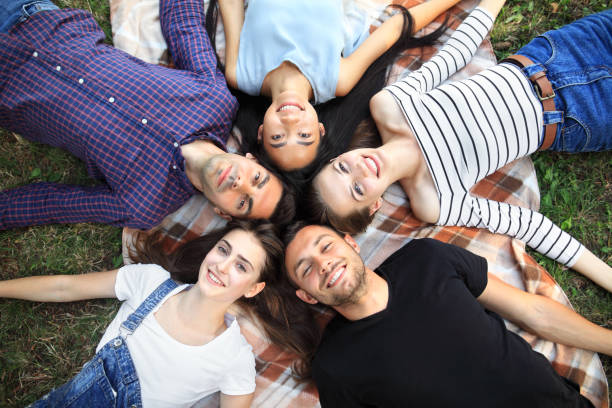 istock Five cheerful friends lying on grass top view portrait 858659096