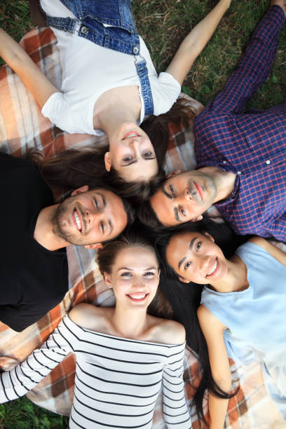 istock Five cheerful friends lying on grass top view portrait 858659124