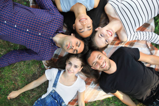 istock Five cheerful friends lying on grass top view portrait 858659150