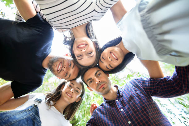 istock Young happy friends in circle hugging and looking down 858659180