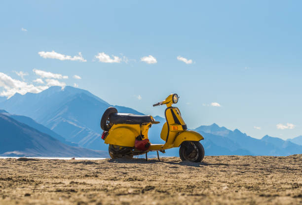 Leh Lardakh,India - 2017 September 26  : old weathered yellow scooter from bollywood movie  parking at highest salt lake in the world  with mountain background