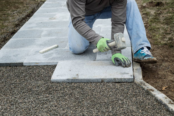 worker hammering the stone plates to install footpath at garden stock photo