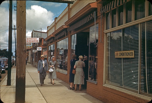 Los Angeles, California, 1953. The Lincoln Bulevard in Los Angeles. Residents of the city stroll along the pedestrian path. Some are in front of the entrance of a cafeteria. Classic American city planning or building.