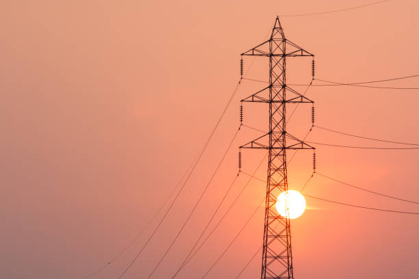 Electricity transmission pylon in the field on sunset. Poles and overhead power lines silhouettes in the dusk. Electric power industry and nature concept. stock photo