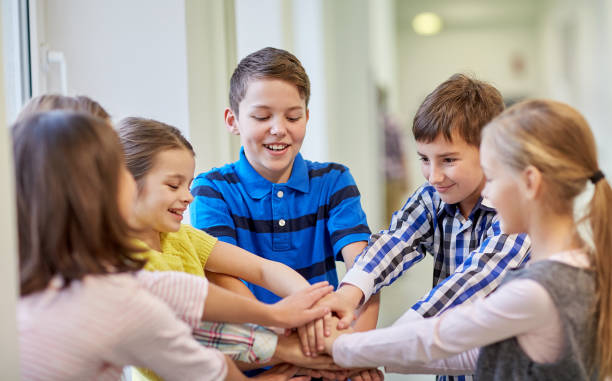 istock group of smiling school kids putting hands on top 858675916