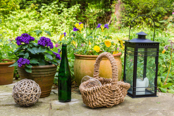still life with flowers, basket, bottle, glasses and lantern in a garden
