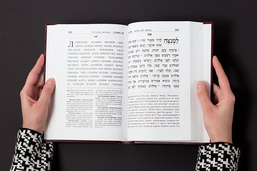 Jewish book, with woman's hand, on black background. Text of the Hebrew, prayer. Woman reading book