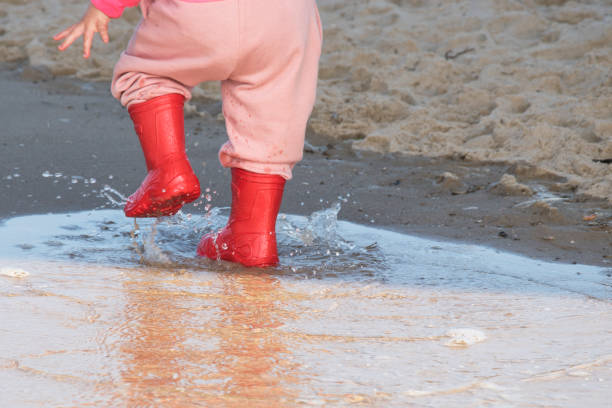 istock wellingtons in puddle.kid rubber boots in the sea background 858688460