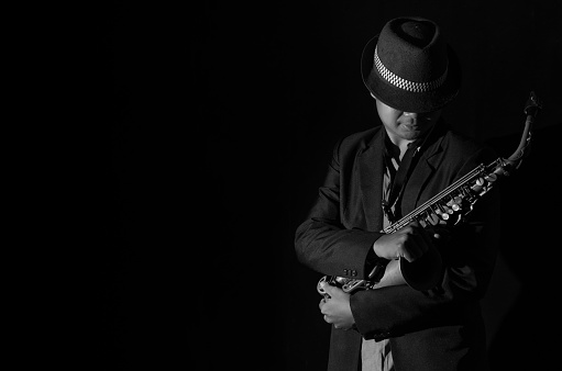 A saxophone player in a dark background, black and white tone