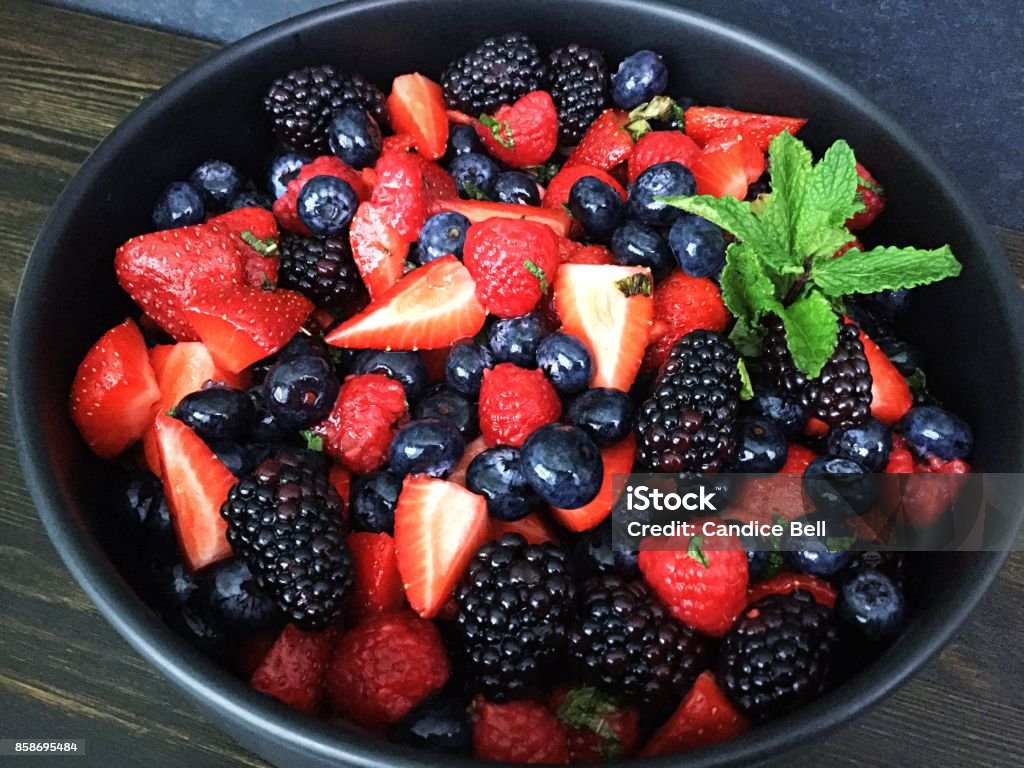 Mixed Berry Salad Berry salad in a black serving bowl garnished with mint leaves. Blackberry - Fruit Stock Photo