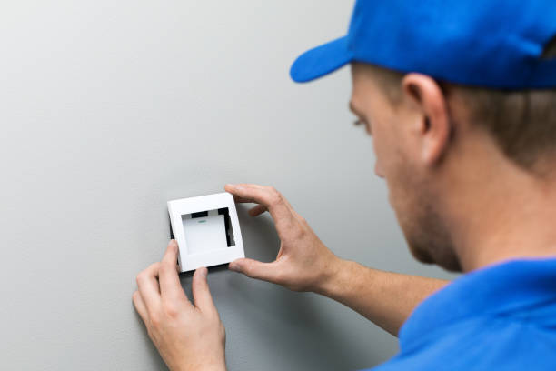 istock electrician in blue uniform installing light switch on the wall 858705896