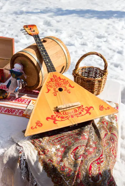 Balalaika and other products of Russian folk art over the snow background