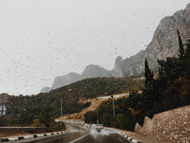water splashes on windshield of car mountain road in rain