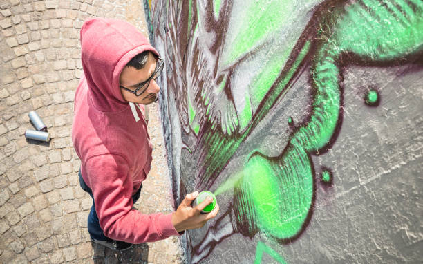 calle artista pintar graffiti colorido en soleada tarde neutro filtro de pared genérico - concepto de arte moderno con chico urbano realizando y preparando murales vivo con atomizador de color verde- - graffiti men wall street art fotografías e imágenes de stock