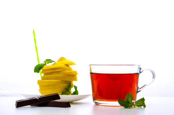 glass cup with tea, mint, chocolate and a cut lemon on a white background glass cup with tea, mint, chocolate and a cut lemon on a white background кружка stock pictures, royalty-free photos & images