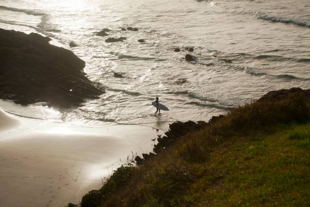 istock Surfer with surfing board walking, beach, cliff, seascape. 858741780