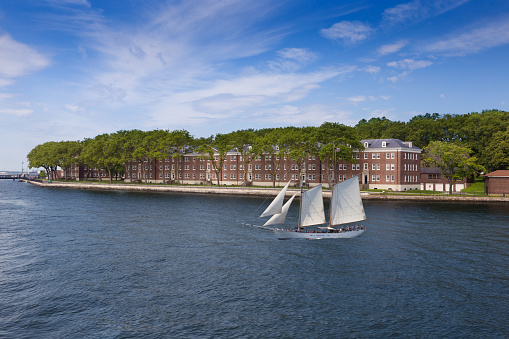 Sailboat (Tall Ship) full of tourists with Governors Island in Background and Cloudy Blue Sky, New York. Canon EOS 6D (full frame) and polarizing filter.