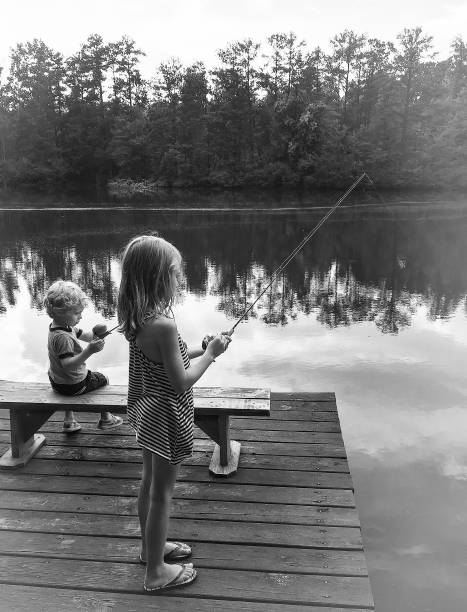 Gone Fishin A Young Boy and Girl Fish from a Dock in Western Georgia black and white bench stock pictures, royalty-free photos & images