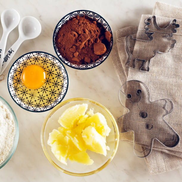 istock Ingredients for baking on a white marble table : flour, eggs, cocoa powder, sugar, butter and measuring spoons, molds 858776378