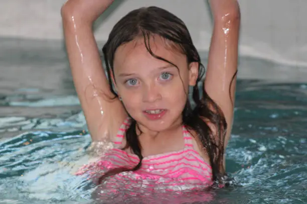 Young girl-child, playing in and, having fun in a swimming pool.