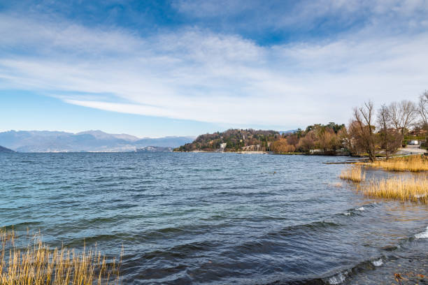 lago maggiore, italien. ispra mit dem kleinen hafen, winterlandschaft von der promenade entlang des sees. im hintergrund die alpen und die städte intra und pallanza - intra coastal stock-fotos und bilder