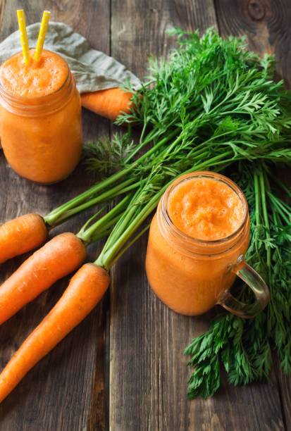 istock Fresh carrot smoothie in glass jars on rustic wooden background 858790302