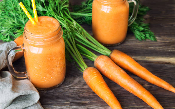 istock Fresh carrot smoothie in glass jars on rustic wooden background 858790318