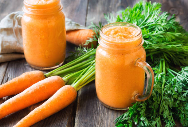 istock Fresh carrot smoothie in glass jars on rustic wooden background 858790320