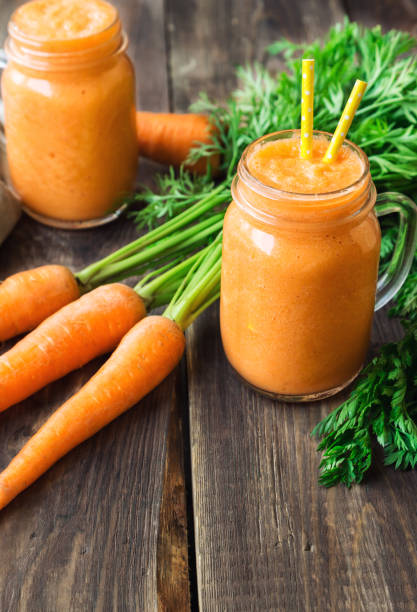 istock Fresh carrot smoothie in glass jars on rustic wooden background 858790330