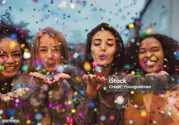 Young Women Blowing Confetti From Hands Stock Photo - Download Image Now - Women, Only Women, Christmas