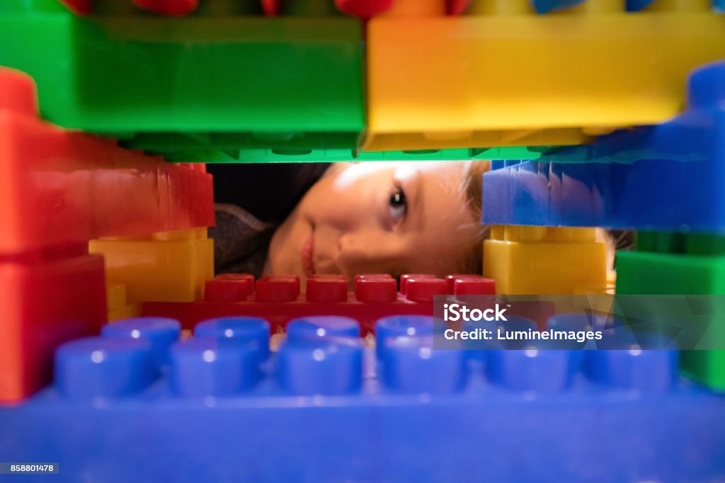 Close up of toy blocks with child in the background. Close up of plastic blocks with child in the background. Boy peeking through construction on toy blocks. Child Stock Photo