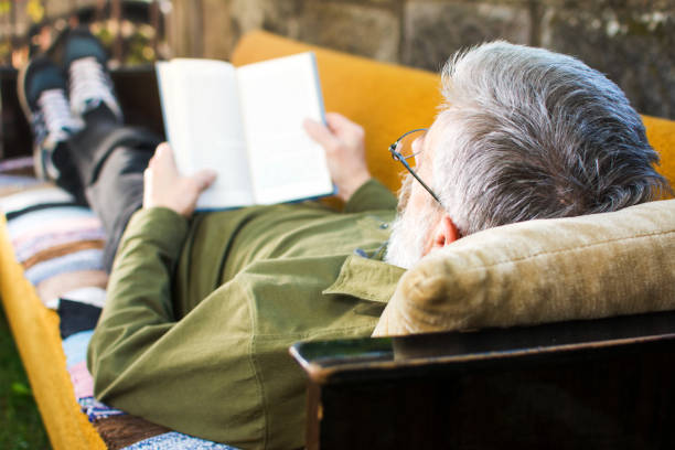 年配の男性が裏庭で本を読んで - senior adult relaxation sofa reading ストックフォトと画像