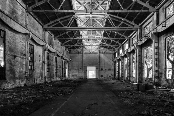 Interior of old factory buildings destroyed. Ruins of industrial enterprise, dark debris destroyed factory premises in factory as result of economic crisis and earthquake.