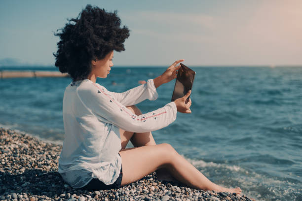 istock Ebony girl taking selfie while sitting on beach 858848234