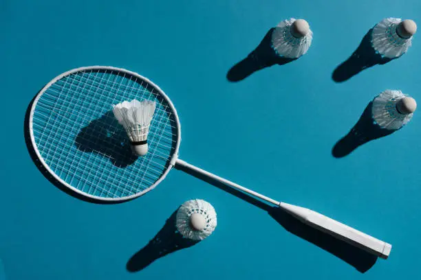 badminton racket and shuttlecocks placed on blue surface
