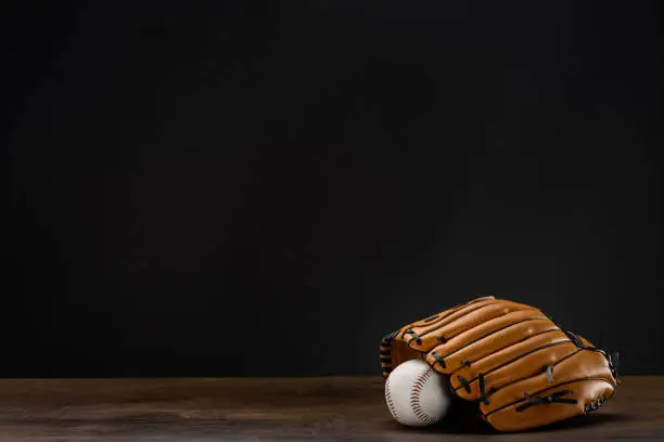 Closeup shot of baseball mitt and ball placed on wooden surface