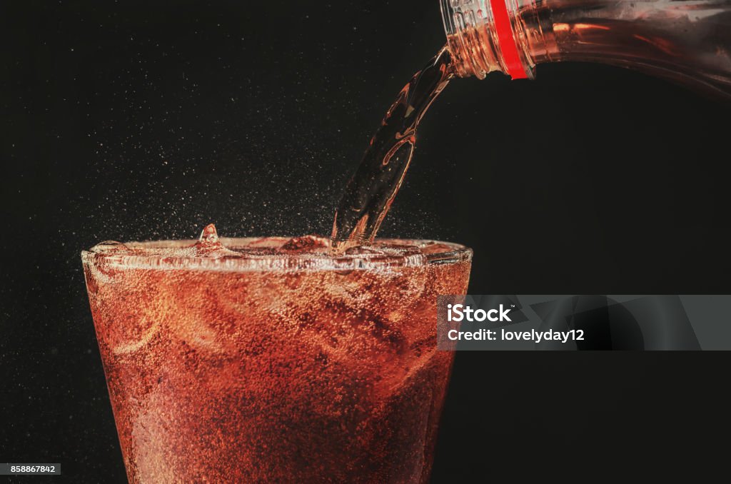Verter la cola de la botella para soda cristal y burbuja sobre fondo negro - Foto de stock de Gaseosa libre de derechos