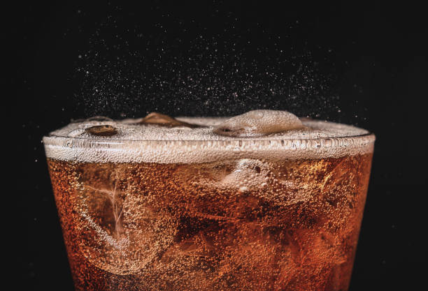 close up ice cola in glass and bubble soda splashing on black background close up ice cola in glass and bubble soda splashing on black background carbonated stock pictures, royalty-free photos & images