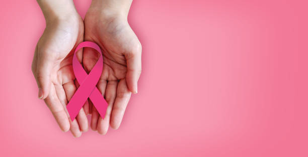 istock Pink ribbon on hands for breast cancer awareness 858874996
