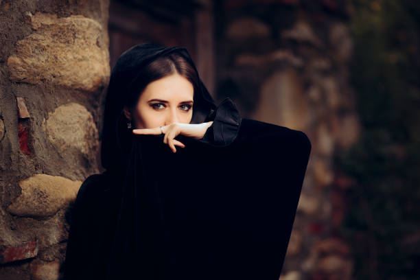 Spooky young girl wearing a hood reading the future in a small crystal ball.