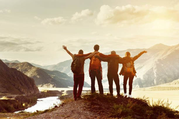 Happy friends travel expedition concept Four happy friends are looking on mountains and having fun together. Space for text. Travel concept adventure stock pictures, royalty-free photos & images