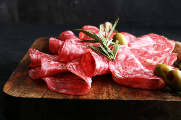 salame em fatias finas em uma cuttingboard de madeira - salame - fotografias e filmes do acervo