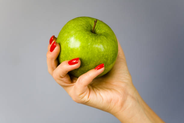 istock A green apple in a graceful female hand. 858931504