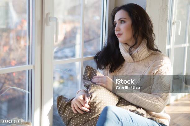 Portrait Of Beautiful Young Woman Smiling In A Knitted Sweater About A Window Christmas Morning Fall Stock Photo - Download Image Now