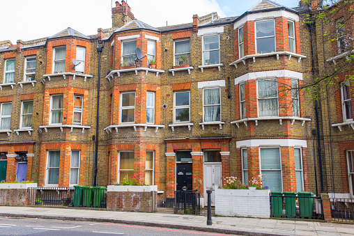 Classic British Victorian restored residential tenement building in red and yellow bricks with classic bay windows.