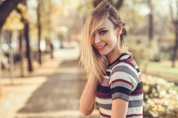 młoda blondynka stojąca na ulicy przesuwając włosy - contemporary fashion model lifestyles blond hair zdjęcia i obrazy z banku zdjęć