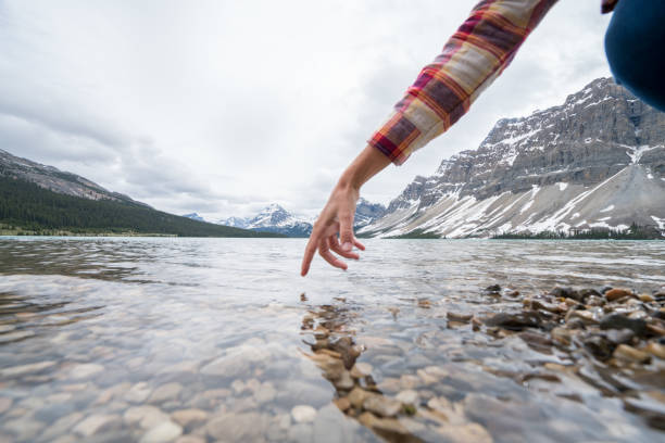 istock Finger touches surface of mountain lake 858948538