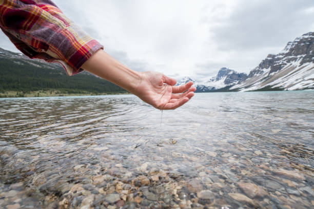 istock Human hand cupped to catch fresh water from mountain lake 858948608